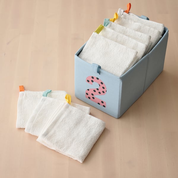Light blue storage box with 2 design holds white washcloths, some folded neatly, others laid out, for versatile use and easy access.