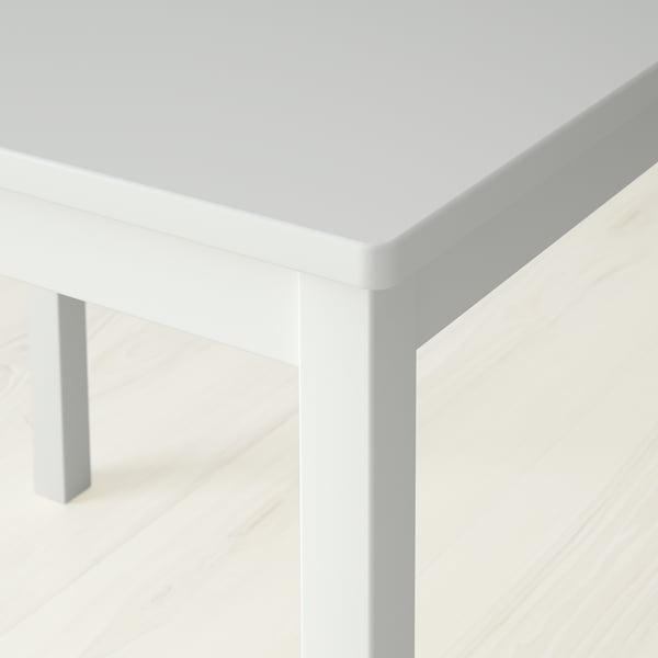 Close-up of a white square table edge, smooth finish, clean design.