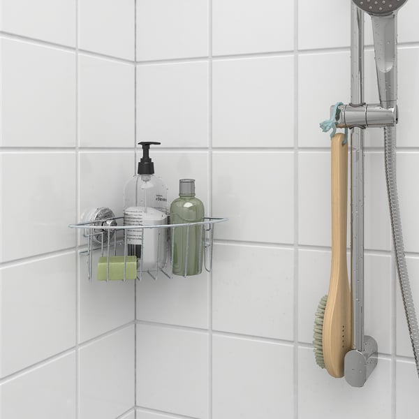 Metal shower caddy with suction cups holds bottles, brush hangs beside.