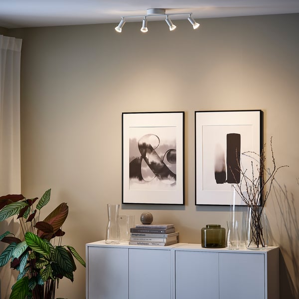 Minimalist living room with ceiling light highlighting art, sideboard with decor.