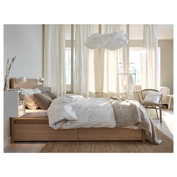 Modern bedroom with KRUSNING lamp, wooden bed, bedside table & wicker chair.