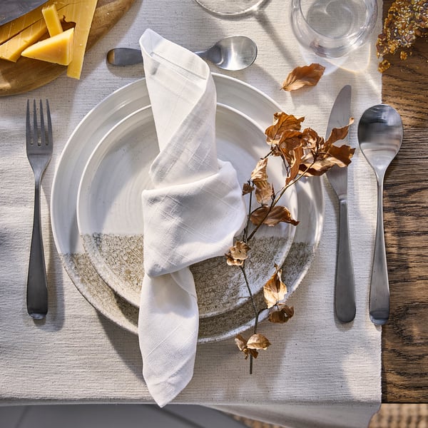 KRUSTISTEL plates on rustic table. White and grey stoneware dishes, larger than cutlery, with unique patterns. Surrounded by fall leaves and cheese.
