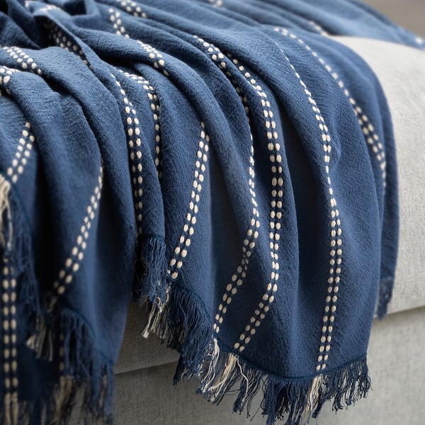 Elegant blue throw with striped dobby weave, fringed ends, draped over couch.
