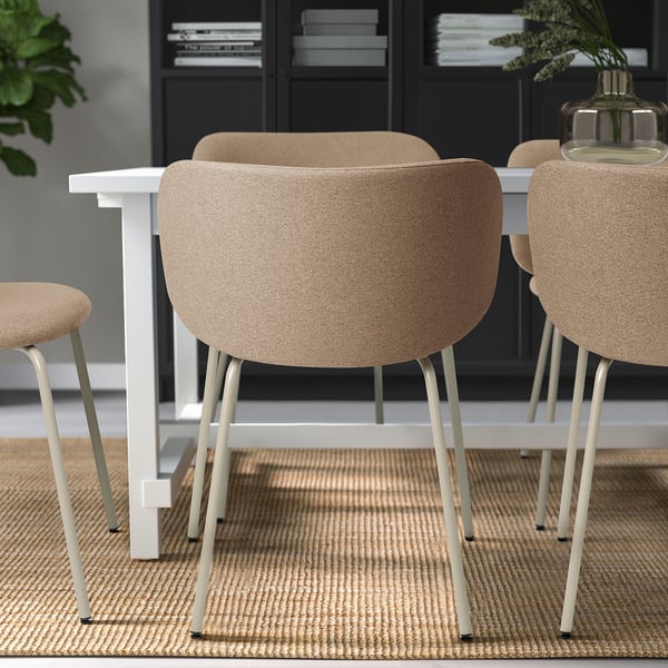 Three beige upholstered dining chairs with metal legs around a white table, offering comfort and style.