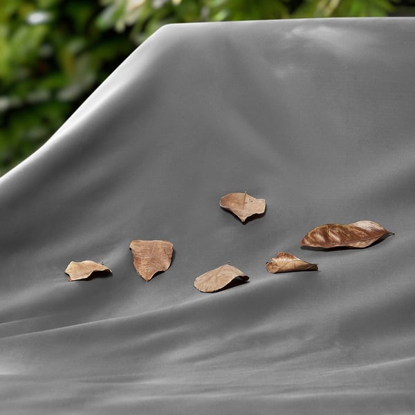 Six brown leaves scattered on a smooth, grey outdoor furniture cover.