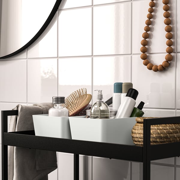 Modern bathroom counter with black shelf, towels, basket, and wall decor