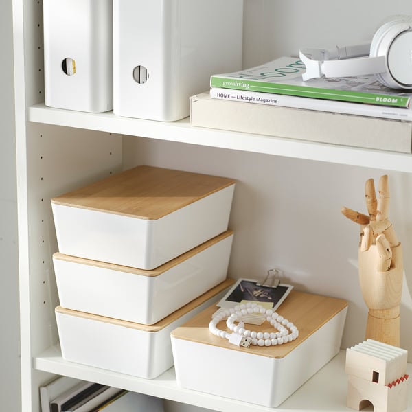 Bookshelf with white and wooden storage boxes, magazines, and a wooden hand figure.