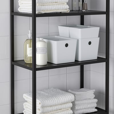 A metal bathroom shelf with KUGGIS boxes, folded towels, and bottles neatly organised.
