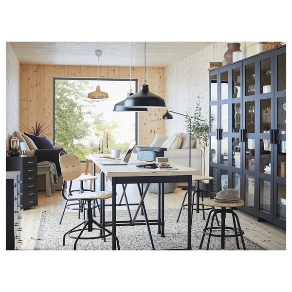 Modern industrial home office with KULLABERG black swivel chairs, large desk, and black lamps.