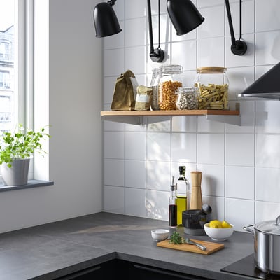 Modern kitchen with KUNGSFORS shelf, jars, and bags. Dark counters, herbs, lemons, and black lamps.