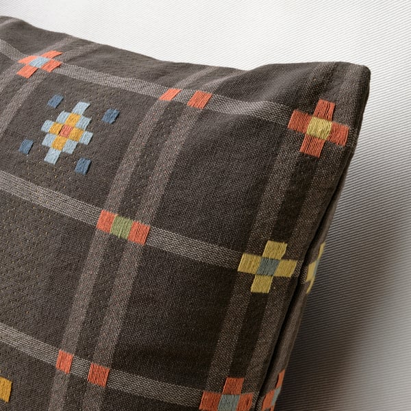 Modern cushion with woven grey fabric and colourful cross patterns.