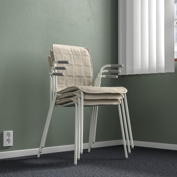 Stacked lightweight, stackable conference chairs with armrests and lumbar support against green wall with outlet.