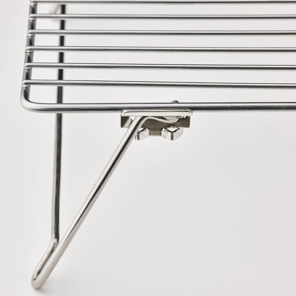 Stainless steel cooling rack, folded neatly, showcasing durable construction and smooth welds.