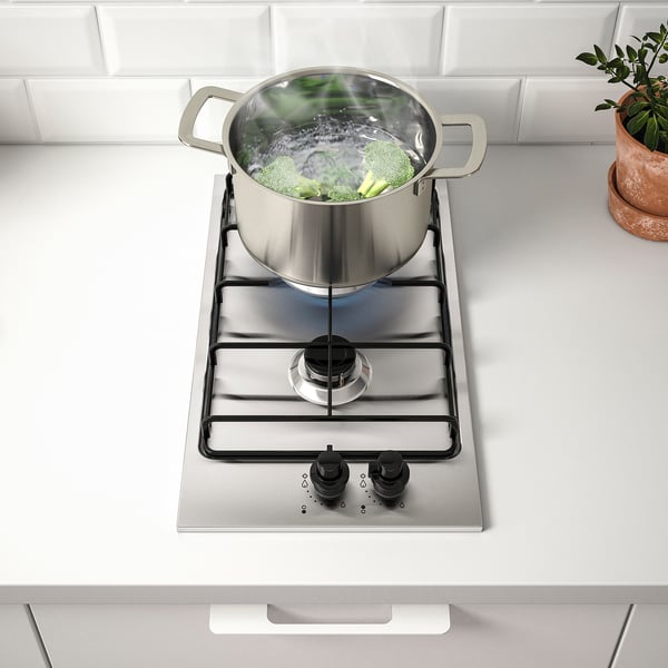 Cooktop with boiling veggies, 2 knobs, visible flame.
