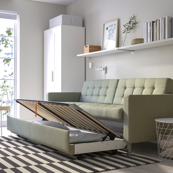 Convertible sofa in living room, transforms to bed with wood slats and storage.