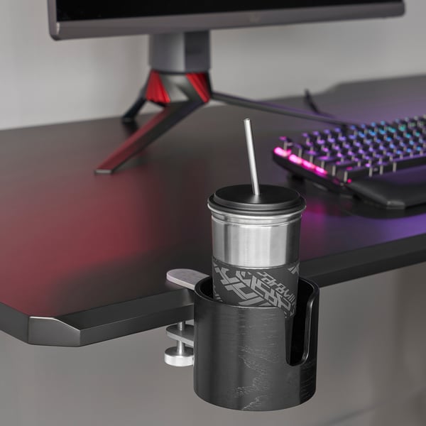 Stainless steel mug in holder clamped to desk near monitor and keyboard.