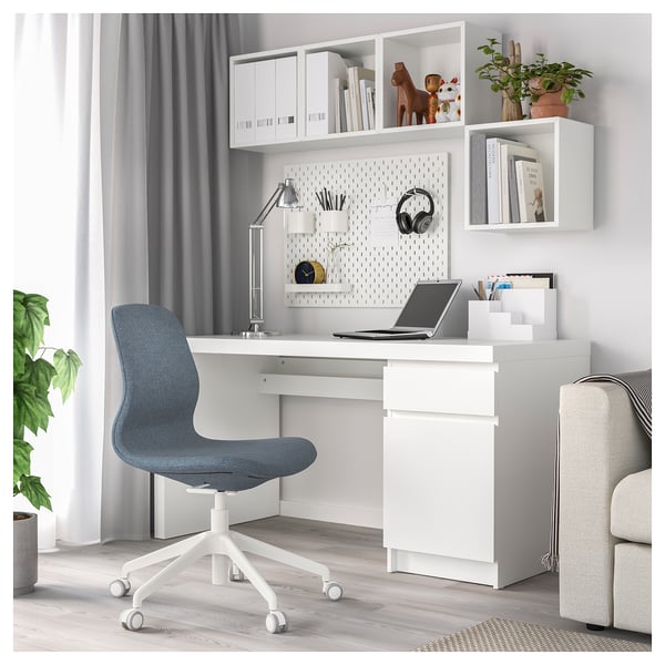 Modern home office with white desk, blue chair, open shelves, and pegboard.