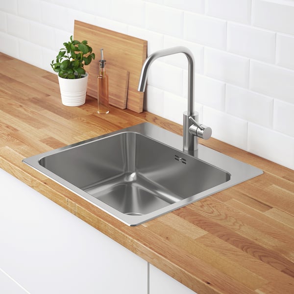 Modern kitchen sink with stainless steel tap, wooden countertop, plant, and soap.