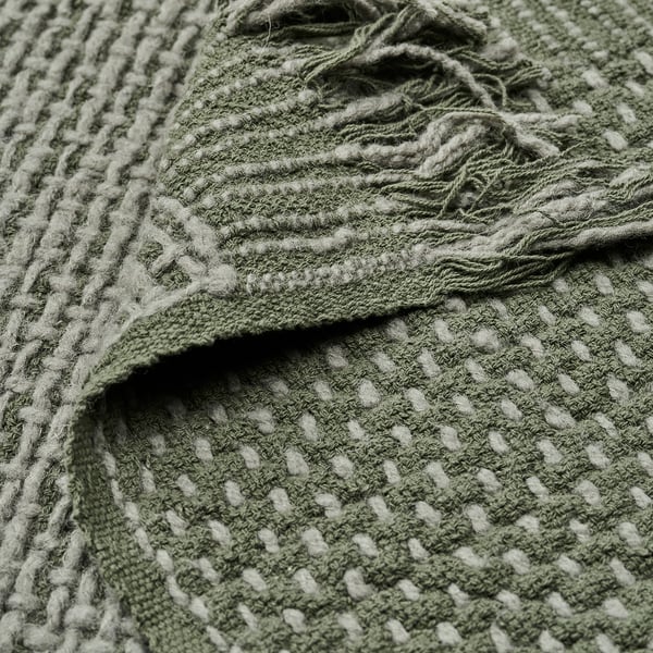 Handwoven throw with dark grey-green tones, featuring cotton and wool blend for warmth and comfort. Intricate texture visible.