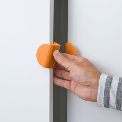 Person attaching orange circular handle to white door. Handle has rounded corners and is easy to grip.