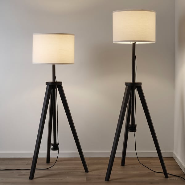 Two black floor lamps with beige shades, adjustable height, hide cords.