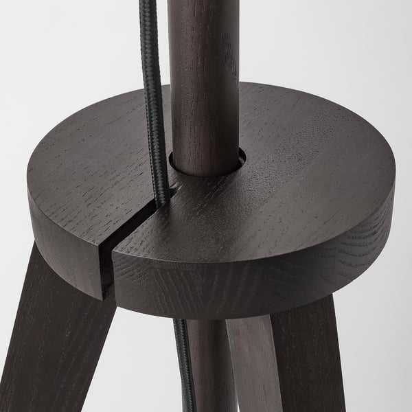 Close-up of modern, high-quality wooden floor lamp base. Round seat, three sturdy legs, and central vertical support tube shown.