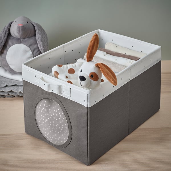 A fabric storage box with a handle and mesh window, showing stuffed toys and baby items inside.