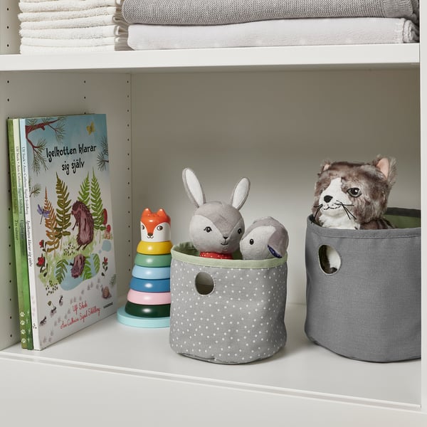Childrens shelf with storage bins: books, plush toys, and fabric containers.