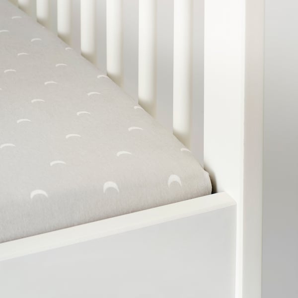 White crib with fitted sheet. Elastic keeps sheet secure. Soft cotton for comfort.