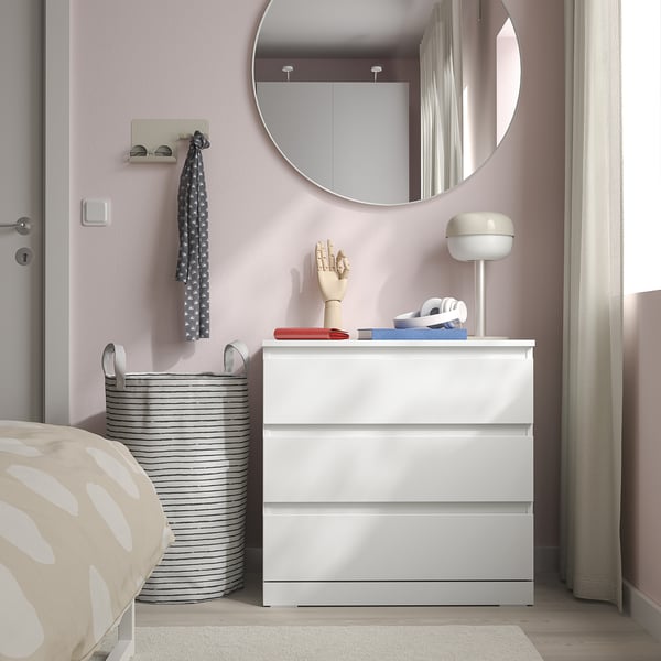 White 3-drawer chest beside bed, under round mirror, with easy-access handles