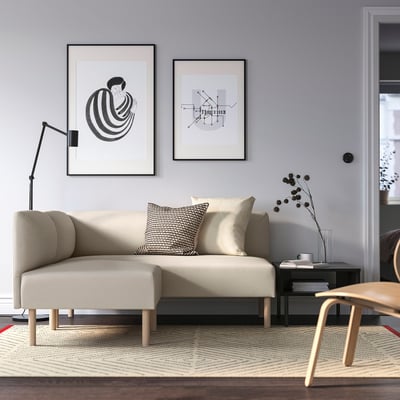 LILLEHEM modular sofa in light beige, centrepiece in minimalist living room with abstract art, beige/brown rug, side table, and tall lamp.