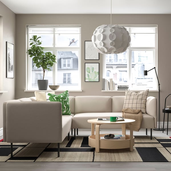 Contemporary living room with beige LILLEHEM sofa, green cushions, wooden coffee table, rug, floor lamp, and potted plant by window.