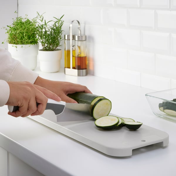 Person slicing cucumber on a white LILLHAVET chopping board.