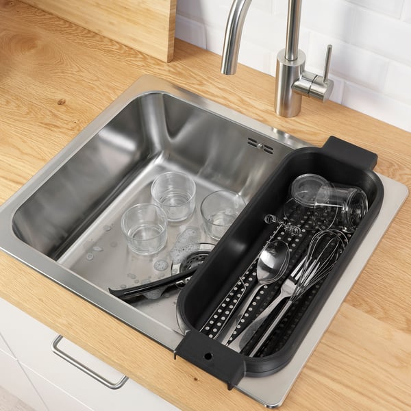 Stainless steel sink with wooden counter and drain tray for glasses and utensils.