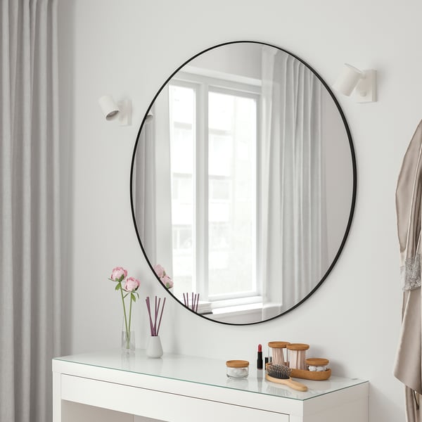 LINDBYN round mirror above vanity, reflecting window, enhancing space.