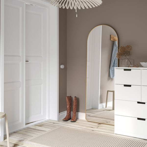 Gold-leaning mirror reflects boots, furniture, adds depth to room.