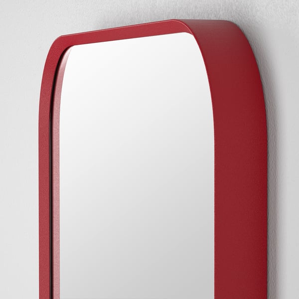 Red rectangular mirror with rounded corners hangs on a white wall. Its sleek frame and modern design add a touch of elegance.