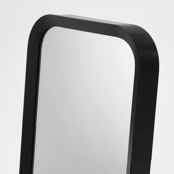 Modern mirror with black, rounded frame, reflecting bright light.