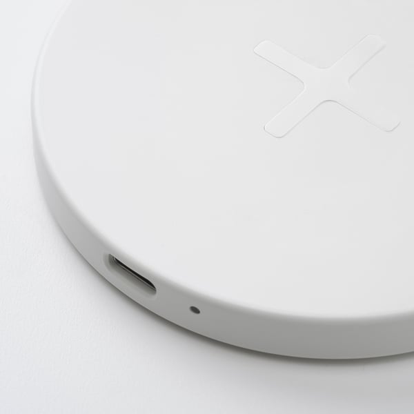 Round white wireless charging pad with flat surface, subtle grey silicone edge, and usb-c slot.