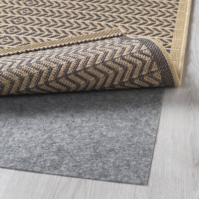 Dark and light grey patterned rug with a black and tan zigzag border and a grey felt rug underlay for anti-slip safety.