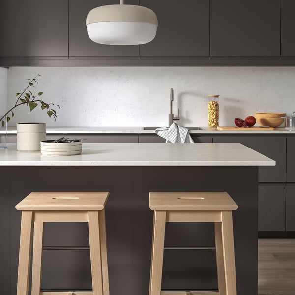 Modern kitchen with dark cabinets, LOCKEBO glass counters, stools, pomegranates, and pendant light.