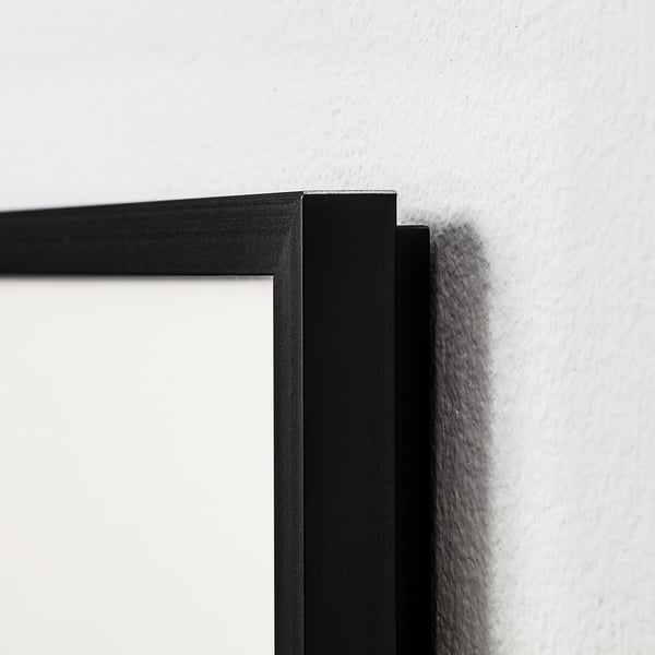 Black picture frame with narrow metal edge mounted on white wall. High-quality finish, clean lines.