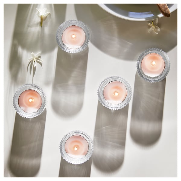 Four lit silver candles reflect softly in a mirror, emitting a romantic glow.