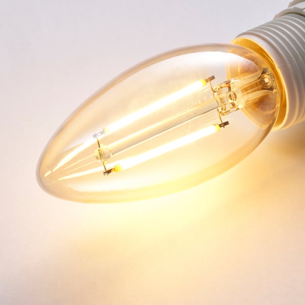 Close-up of a warm-glowing, energy-efficient led bulb, showcasing its intricate glass design and lit filament.