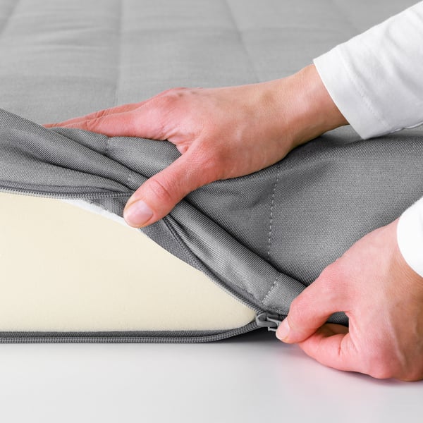 Person opening grey foam mattress cover, demonstrating easy access and maintenance.