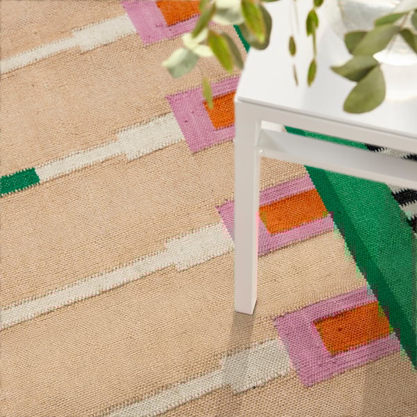 Colourful woven rug with jute and wool on floor near plant.