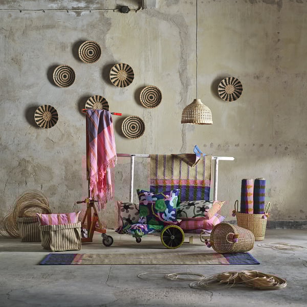 Cosy room with textiles: bright throw, striped, on tricycle, baskets, cushions.