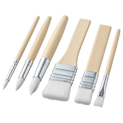 Six white brushes with wooden handles, ferrules, and various bristle shapes, laid out on a white background.