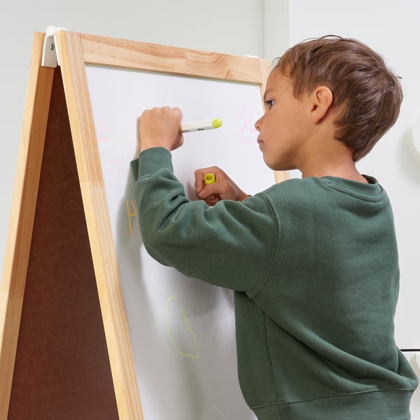 Boy draws with whiteboard pen on kid-safe whiteboard.