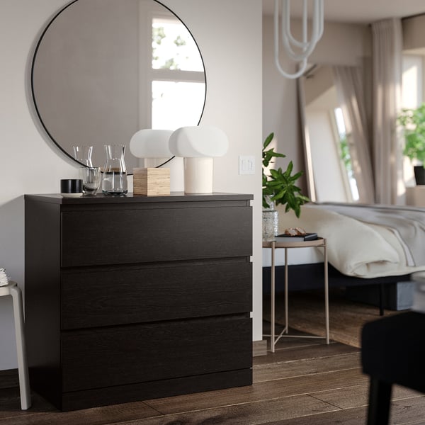 Modern bedroom with MALM 3-drawer dresser in black, round mirror, white lamps, and bed.